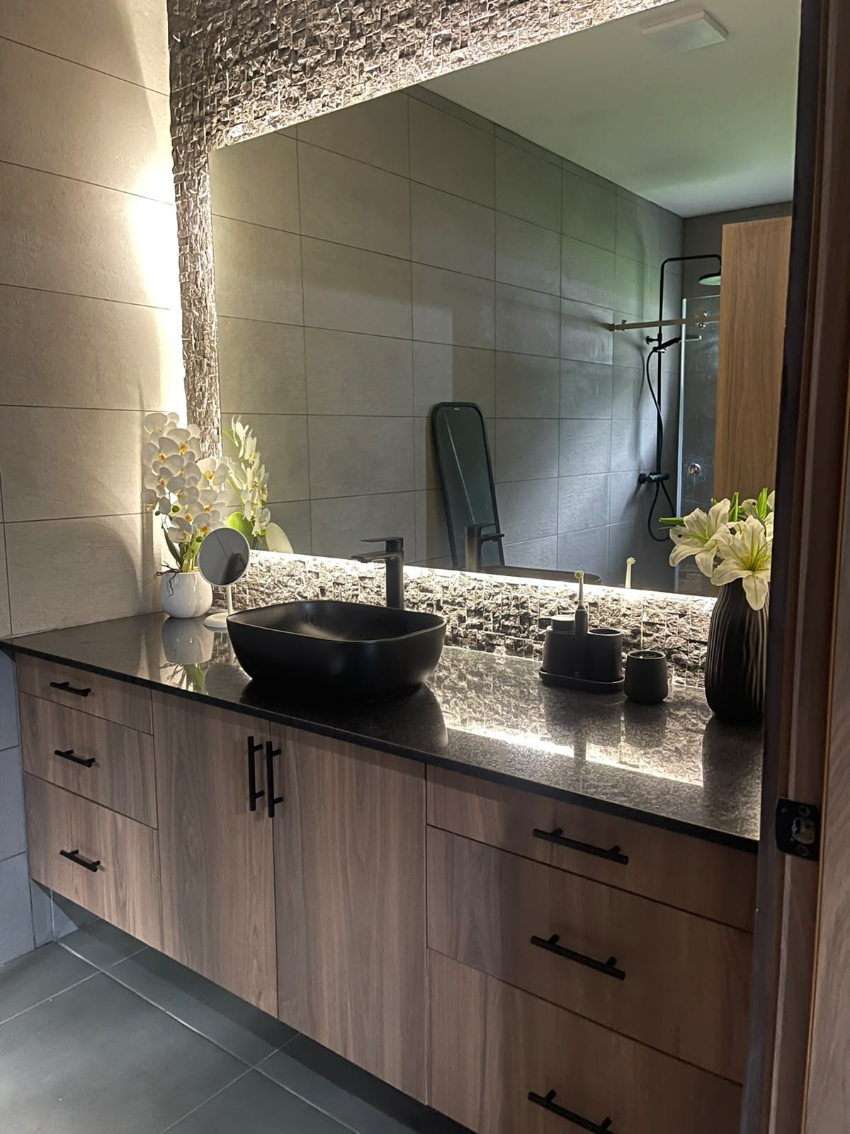 Baño con piedra natural y espejo retroiluminado